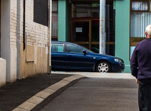 photo of a man walking up an alleyway facing away from the viewer
