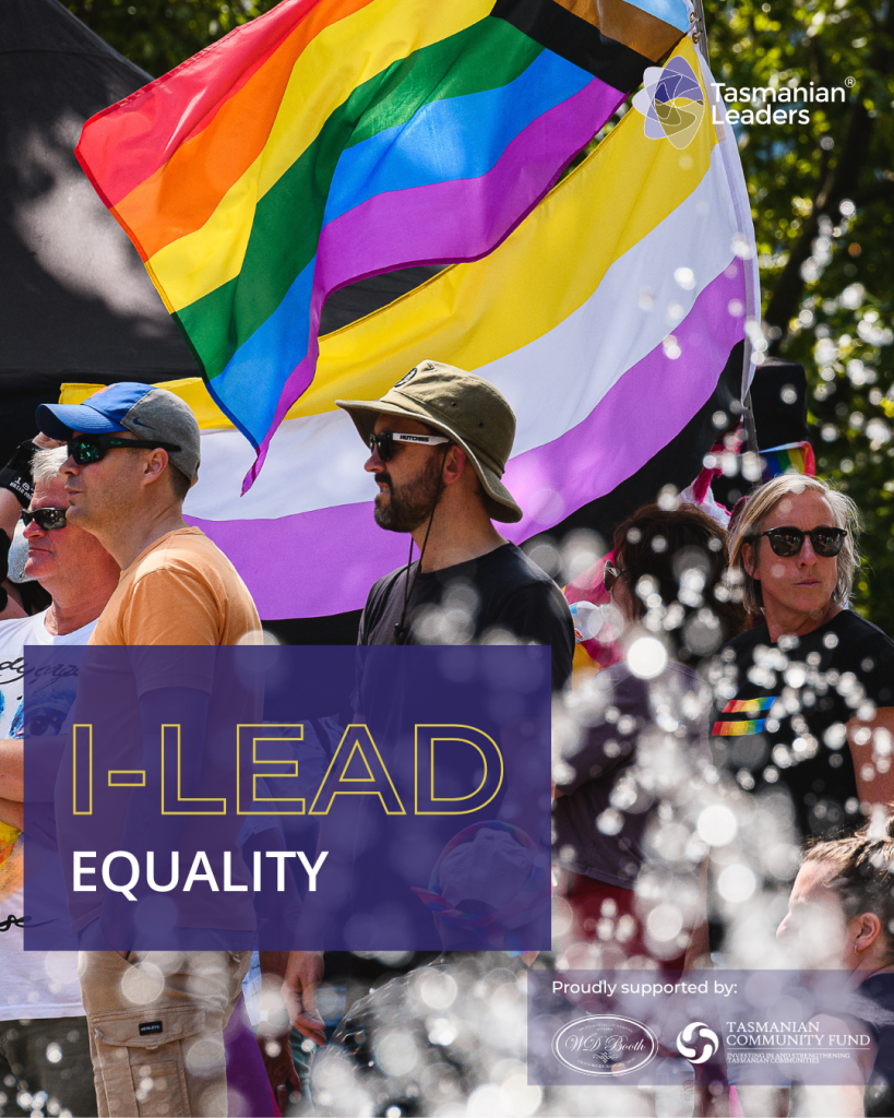 a group of people standing with sunglasses and hats, there is a spray of water in the foreground and a PRIDE flag behind them