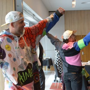 image of two men standing, stretching their arms wide and smiling
